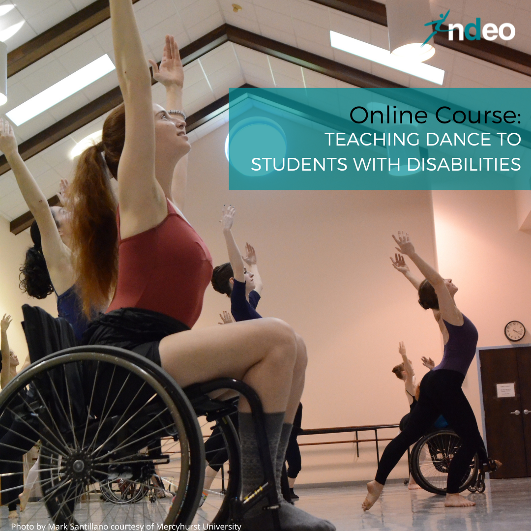 Female in red leotard sitting in wheelchair in a dance class with arms raised above head